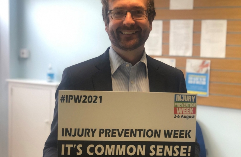 Alexander Stafford MP holding an Injury Prevention Week sign
