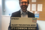 Alexander Stafford MP holding an Injury Prevention Week sign