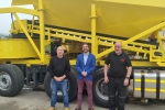 Alexander Stafford MP stands in front of a digger at Mixamate in Dinnington with two other people